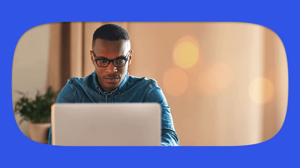 Homem jovem usando óculos e consultando precatório pelo CPF em um laptop, com fundo difuso de luzes quentes.