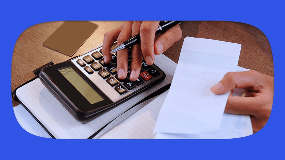 Pessoa usando calculadora para calcular o juros abusivo e fazendo anotações em um caderno.