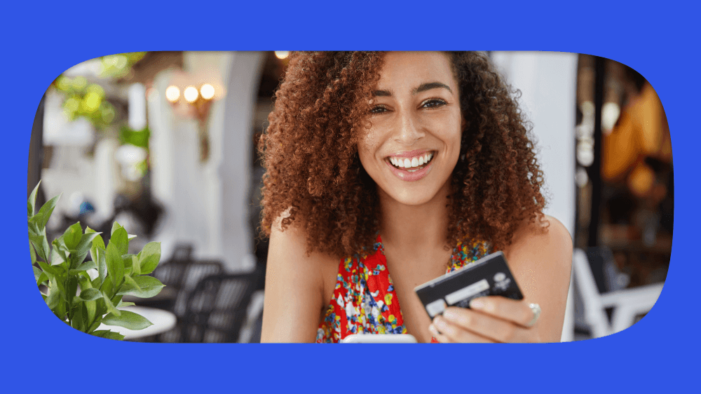 Mulher sorrindo com cartão de crédito na mão