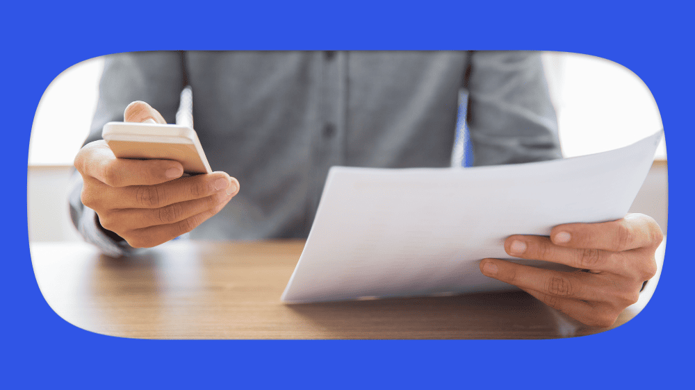 Pessoa segurando um smartphone e um boleto, verificando se o boleto é falso.