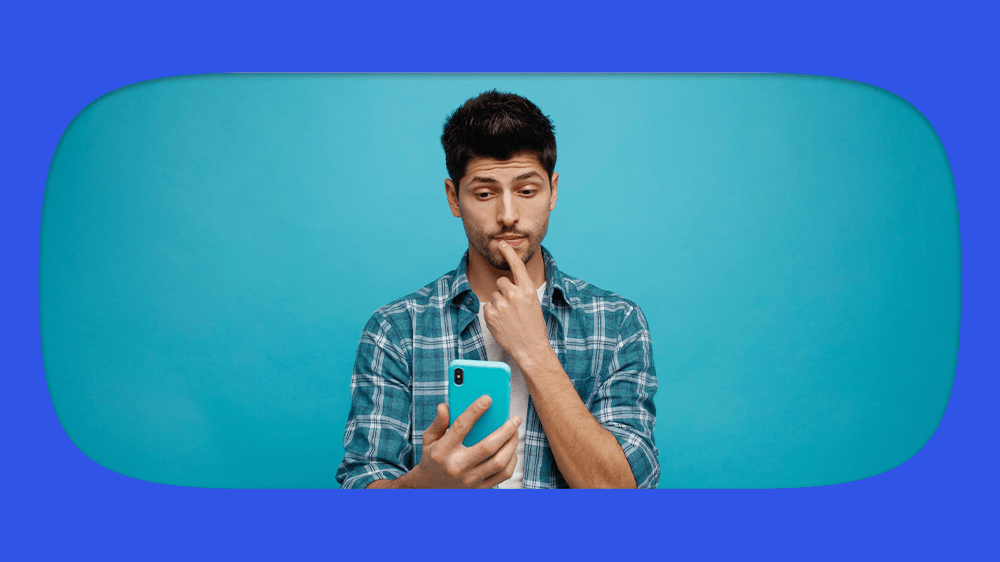 Homem verificando no celular se o título de eleitor cancelado suspende cpf. Imagem de pessoa jovem com camisa de flanela azul, fundo azul claro.